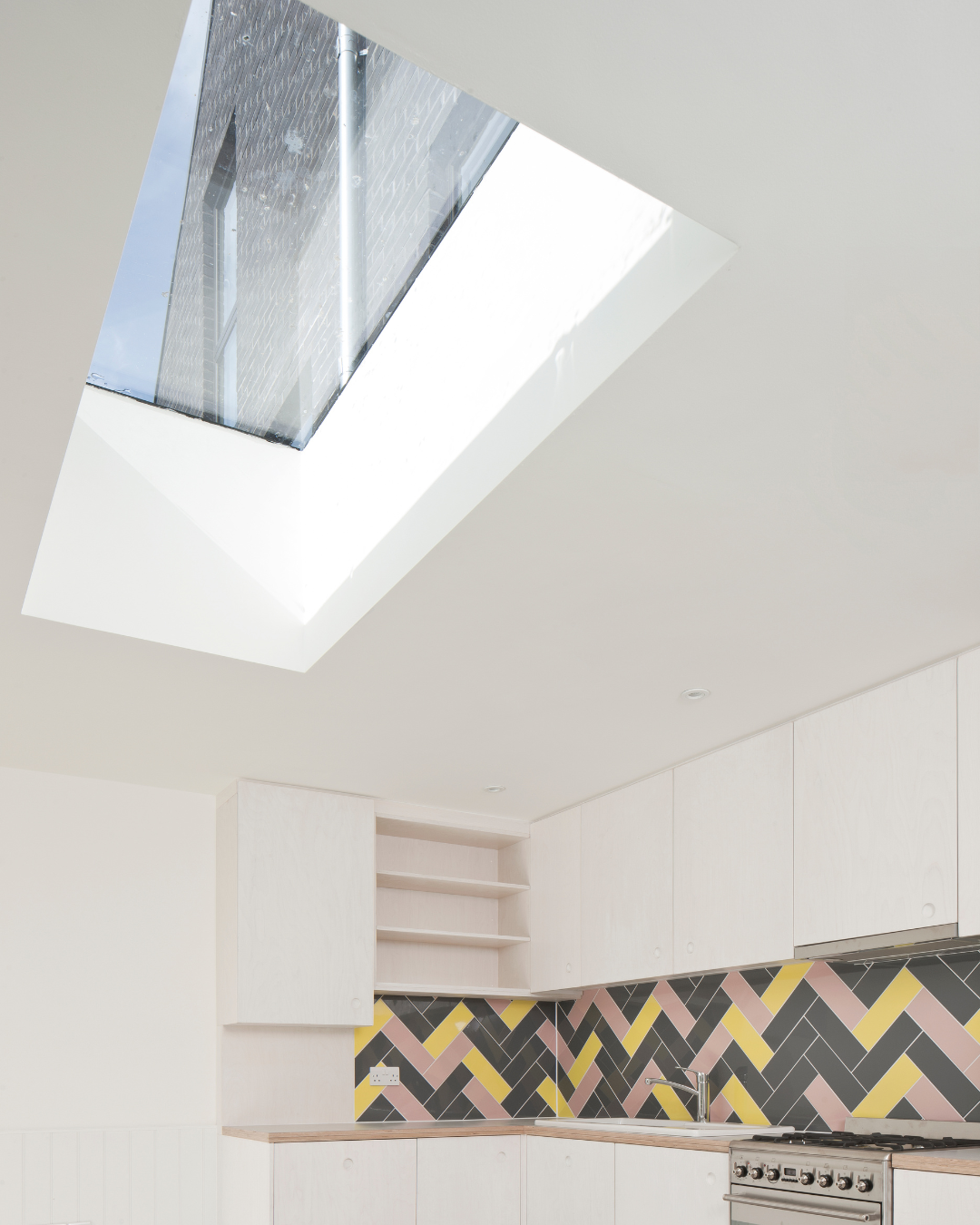 rooflight installed in modern kitchen with white walls and a yellow and grey backsplash 