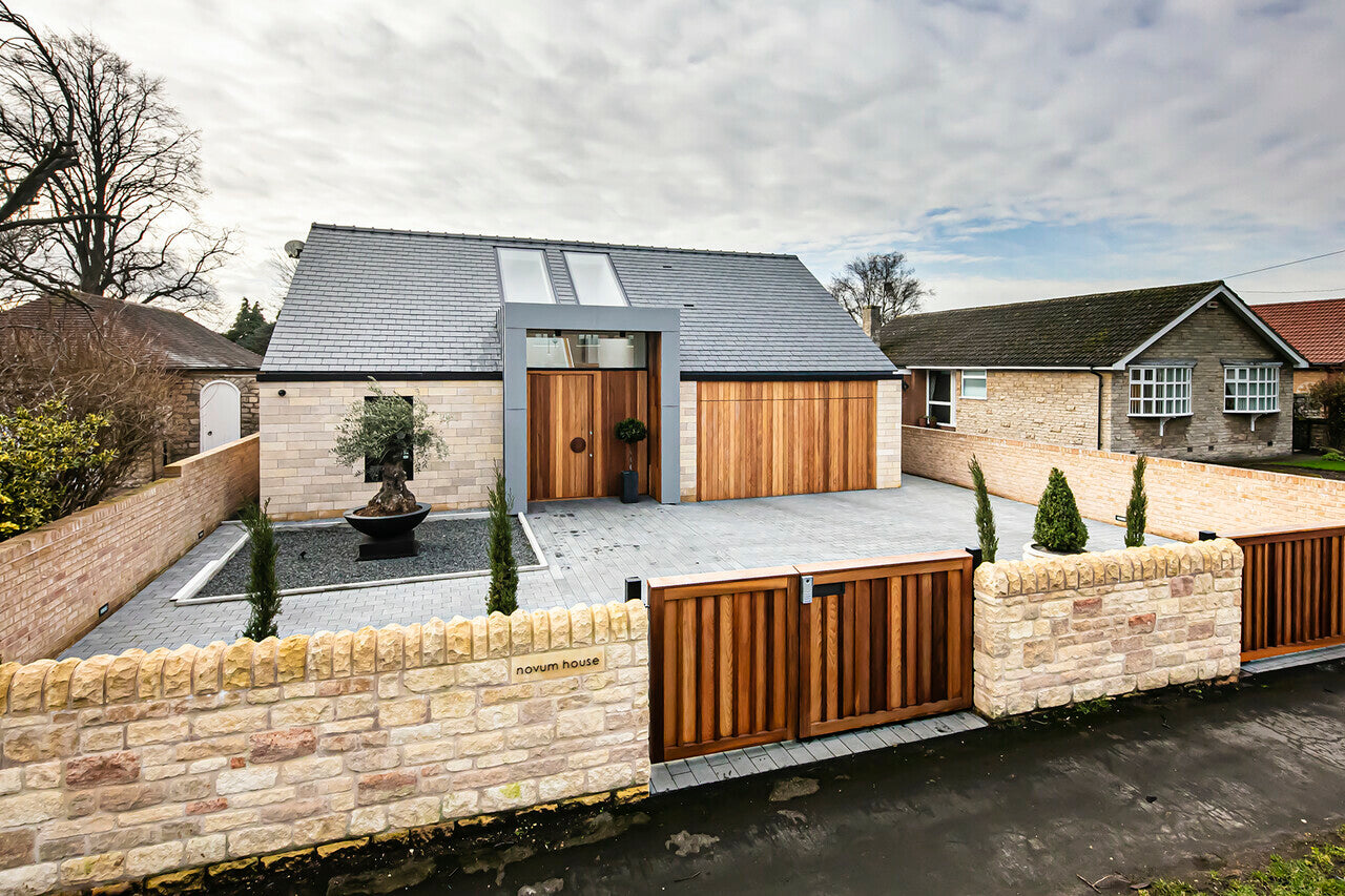 fixed roof window installed on a modern home with a grey driveway, beige stone wall and wooden gate