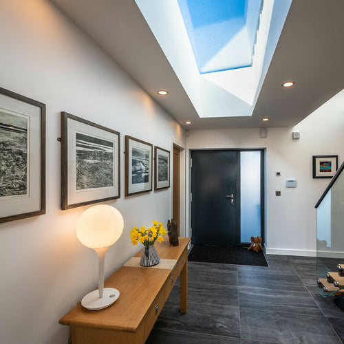 Flat rooflight installed in modern hallway with a black door and pictures on the wall to the left, dark grey flooring