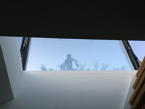 inside view of an open rooflight with a ladder to the right, shadow of woman with a watering can