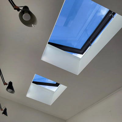 two open rooflights in a white ceiling, with blue sky seen through the glass